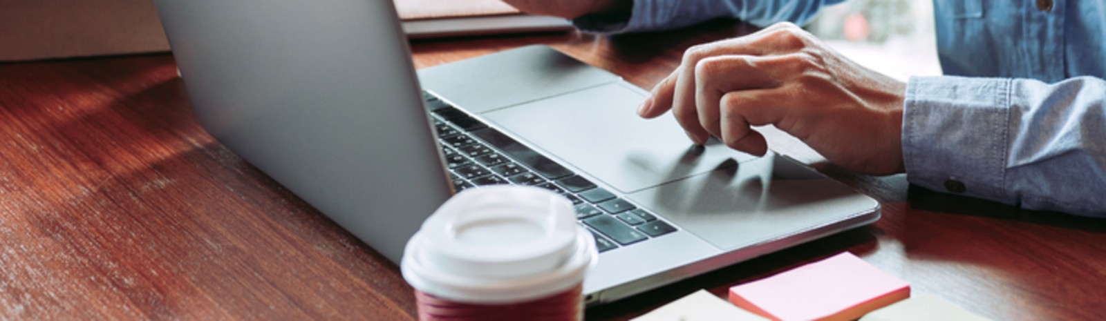Male using laptop with coffee and sticky notes on table